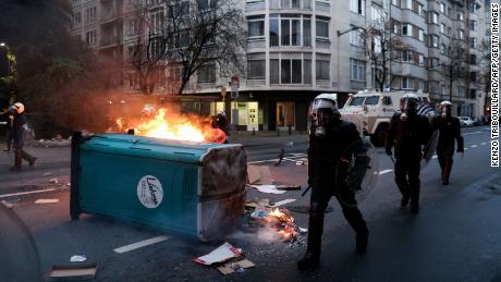 Belgian riot police walk past a fire as clashes erupt in Brussels during a demonstration against Covid-19 measures on December 5, 2021. 