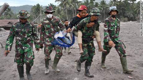 Members of a search and rescue team carry a villager during an operation at the Sumberwuluh village on December 6, 2021.