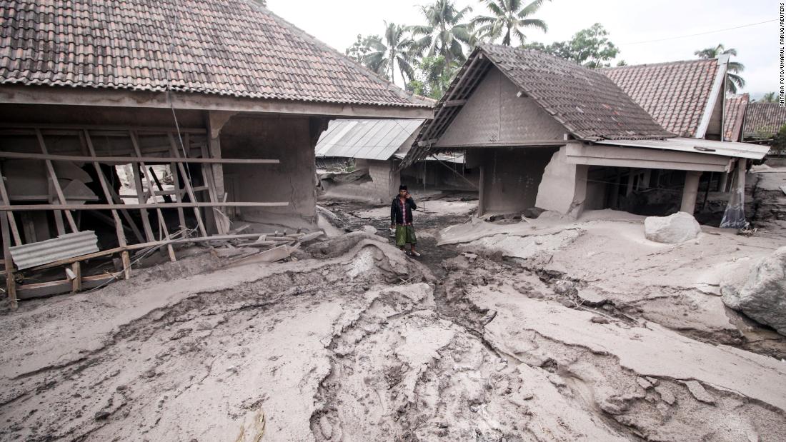 A man stands amid houses that were covered by volcanic ash in the village of Sumberwuluh.