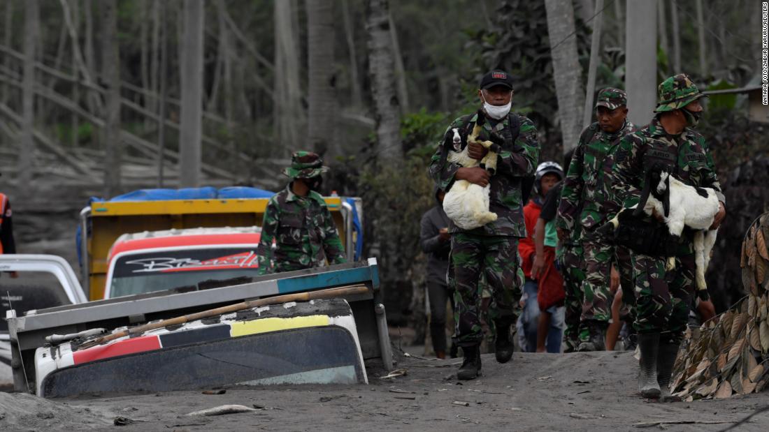 Indonesian military officers carry livestock away from the evacuation zone on Monday.