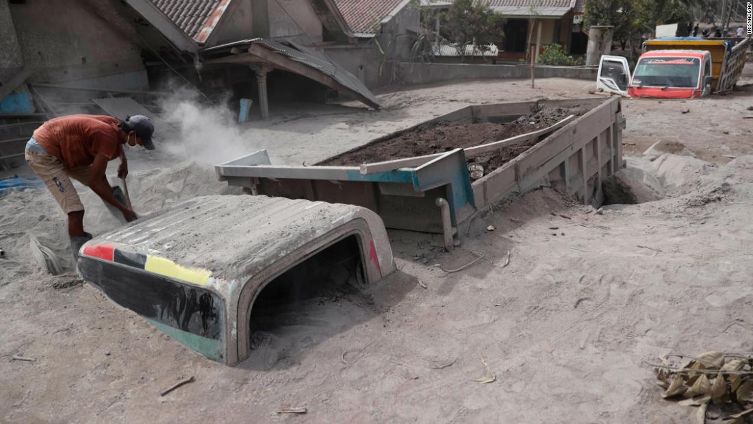 A man inspects a truck buried in the ash on Sunday.