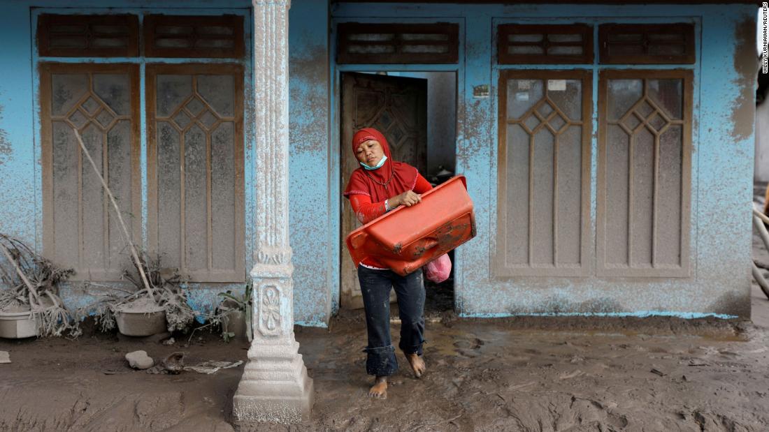 Siti Animah, 42, gathers usable goods from her damaged house Curah Kobokan village, Pronojiwo district, on Tuesday.