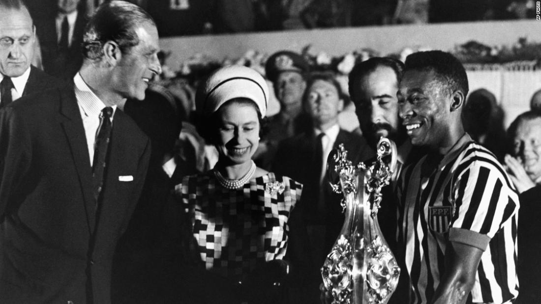 Britain&#39;s Queen Elizabeth II, accompanied by her husband, Prince Philip, award a trophy to Pelé after watching a match in Rio de Janeiro in 1968.