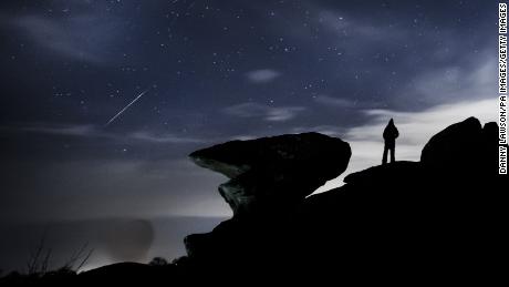 A man watches a meteor during the Geminid meteor shower over Brimham Rocks, a collection of balancing rock formations in the Nidderdale Area of Outstanding Natural Beauty in North Yorkshire. (Photo by Danny Lawson/PA Images via Getty Images)