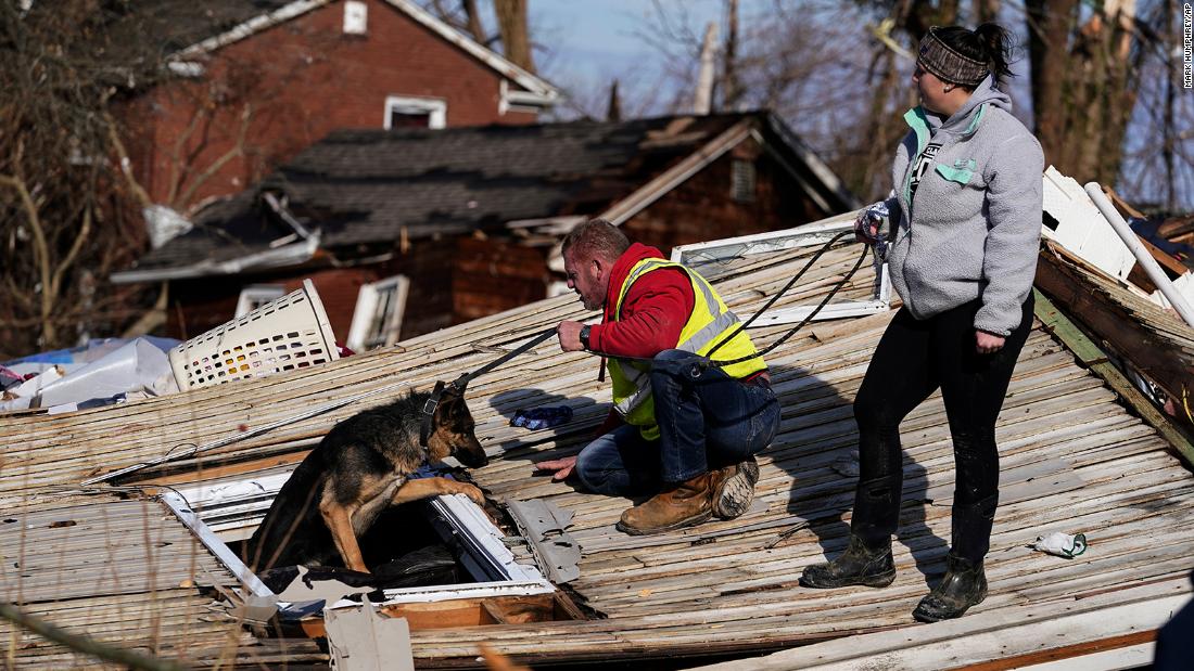 Chris Buchanan, center, and Niki Thompson, right, attempt to rescue Cheyenne, a dog, from a tornado-damaged home in Mayfield on Saturday.