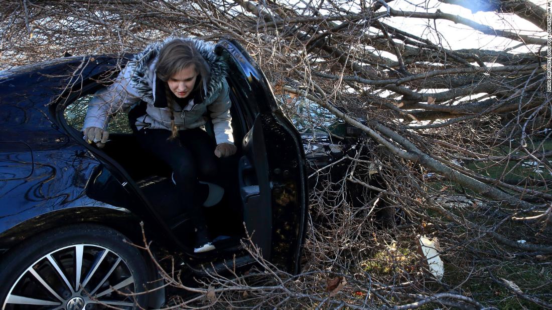 Hannah Binder climbs out of her car in Edwardsville, Illinois, on December 13. She was gathering some personal items from the car after it had been hit by a tree on Friday.