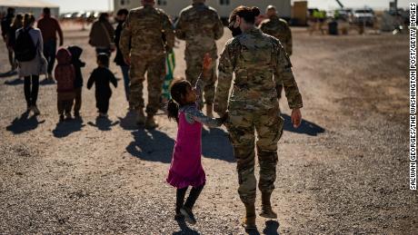 A U.S. military service member hold the hands of an Afghan girl at Holloman Air Force Base in Alamogordo, New Mexico, on November 4, 2021. 