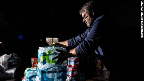 A volunteer carries bottled water to be donated at His House Ministries in Mayfield.