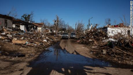 Water from a broken pipe pours into the street from a destroyed home in Dawson Springs.