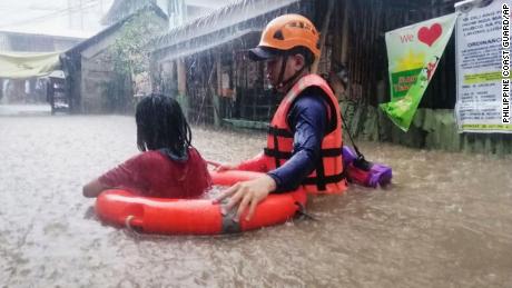 A rescue worker helps a girl wade through flooding caused by Typhoon Rai in Cagayan de Oro City, the Philippines, on December 16.