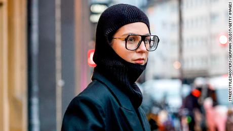 COLOGNE, GERMANY - NOVEMBER 19: Influencer Maria Barteczko, wearing a black balaclava beanie by Weekday, a black oversized coat by PAPER MOON Seoul, a black long sleeve by 032c, a grass green terry cloth pouch by Bottega Veneta and black oversized Aviator glasses by Victoria Beckham, during a street style shooting on November 19, 2021 in Cologne, Germany. (Photo by Streetstyleshooters/Getty Images)