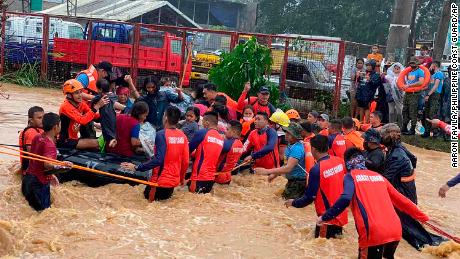 Rescuers help residents over floodwaters caused by Typhoon Rai as they are evacuated to higher ground in Cagayan de Oro City, southern Philippines on December 16, 2021. 