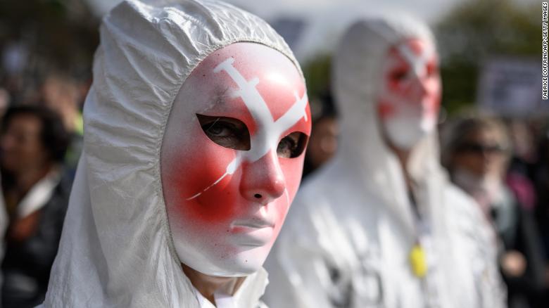 A protester wears a mask depicting syringes during a rally against coronavirus measures, Covid-19 health pass and vaccination in Geneva on October 9, 2021.