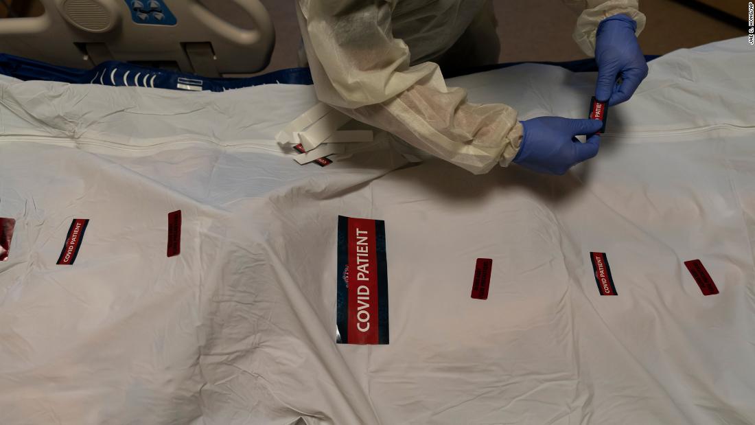 Registered nurse Bryan Hofilena attaches stickers on a body bag of a patient who died of coronavirus at Providence Holy Cross Medical Center in Los Angeles December 14.