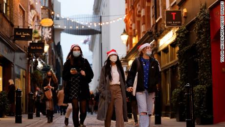 Pedestrians, some wearing face coverings to combat the spread of Covid-19, walk past shops in Covent Garden on the last Saturday for shopping before Christmas, in central London on December 18, 2021.