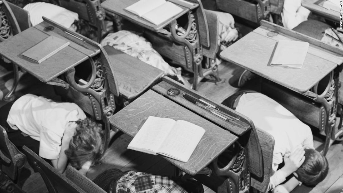 School children learn to protect themselves in case of nuclear attack by practicing a duck-and-cover drill in their classroom in 1951.
