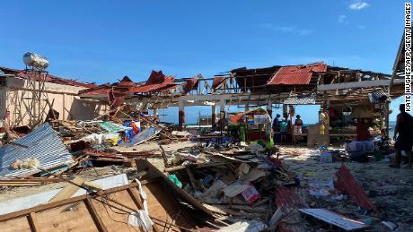 Moradores estão ao lado de um prédio comercial destruído no município de General Luna, na ilha de Siargao, na província de Surigao del Norte, um dia depois que o furacão Ray devastou a ilha.  