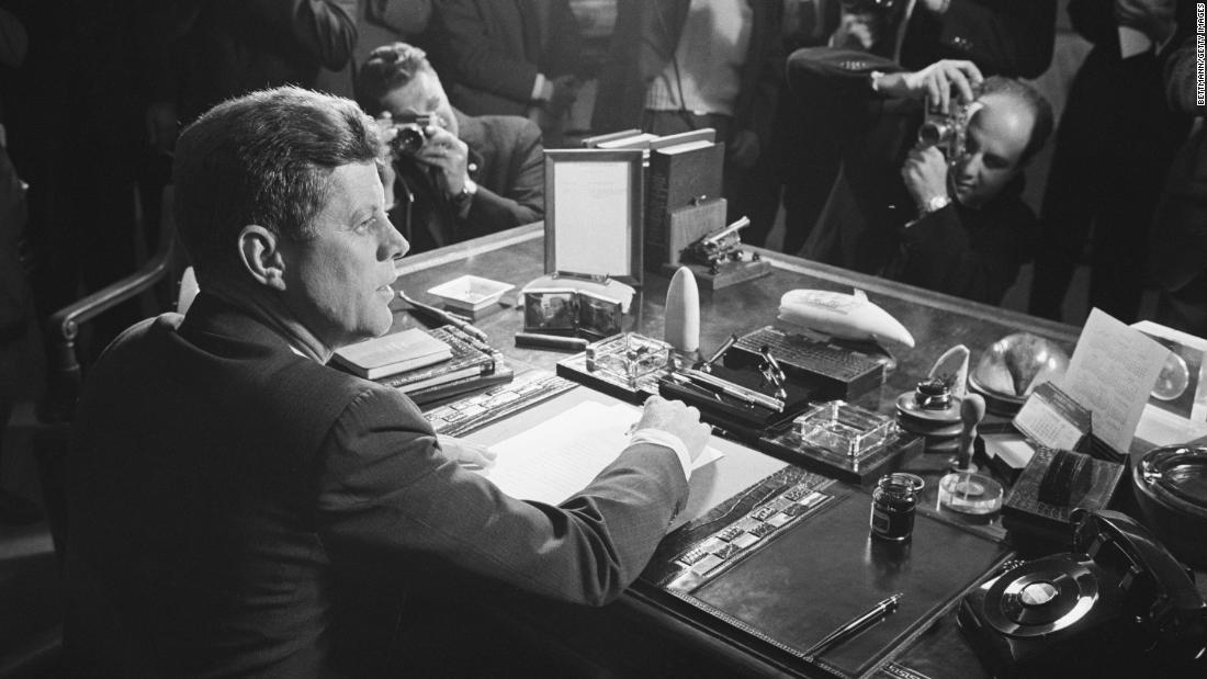 Reporters take pictures of US President John F. Kennedy behind his desk after he signed the arms embargo against Cuba in 1962. The embargo effectively quarantined Cuba. In 1961, a US-organized invasion of 1,400 Cuban exiles was defeated by Castro&#39;s forces at the Bay of Pigs. President Kennedy took full responsibility for the disaster. The next year, the Soviet Union installed nuclear missiles on Cuba capable of reaching most of the US. Kennedy ordered a naval blockade of Cuba until the Soviets removed the missiles. Six days later, the Soviets agree to remove the missiles, defusing one of the most dangerous confrontations of the Cold War.