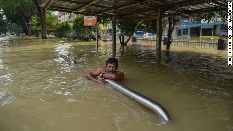 A man holds onto barriers as he waits to be evacauted by a rescue team in Shah Alam, Selangor, Malaysia, on December 20.