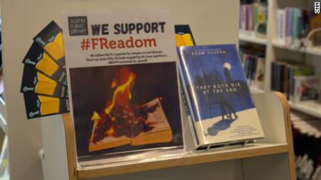 A sign at a branch of the Austin Public Library encourages readers to check out young adult books recently targeted by Texas lawmakers.  Next to the sign there is a copy of 