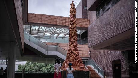 two children looking at "  pillar of shame "  A statue on the campus of the University of Hong Kong on October 15, 2021, in Hong Kong.