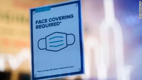 A sign reminds customers that masks are required in their store in New York, Monday, Dec. 13, 2021. A mask mandate for shops and other indoor spaces in New York state took effect Monday as officials confront a surge in COVID-19 cases and hospitalizations. (AP Photo/Seth Wenig)