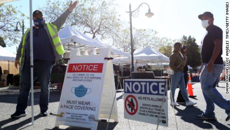 People entering the farmers market are directed to hand washing stations in Whittier on Dec. 4, 2020 in Los Angeles.
