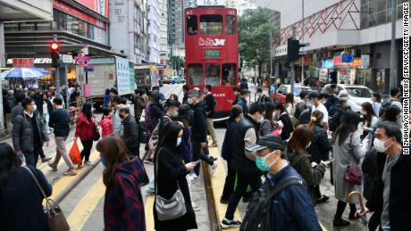 People wearing face masks cross a street in Hong Kong on December 21.