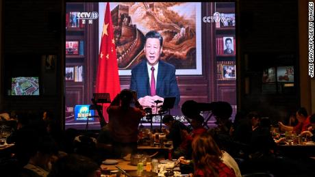 People have their dinner at a restaurant as a screen broadcasts Chinese President Xi Jinping delivering his New Year speech in Beijing on December 31, 2021. 