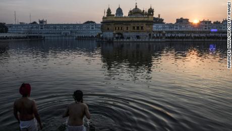 Sikh devotees take a dip in the holy Sarovar (water tank) during the last sunset of 2021 on the eve of New Year 2022, at the Sikh shrine Golden Temple in Amritsar on December 31, 2021.