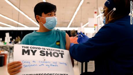 A teenager holds a sign in support of Covid-19 vaccinations as he receives his first Pfizer dose in May 2021 in Des Plaines, Ill. 
