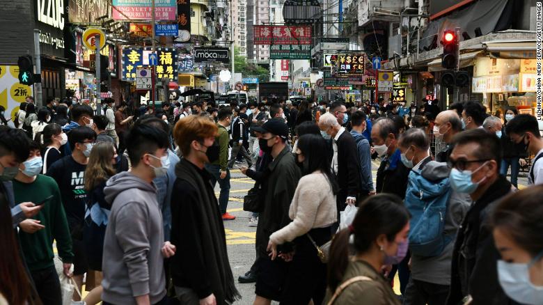 People wearing face masks cross a street in the densely populated Mong Kok district of Hong Kong on December 22, 2021.