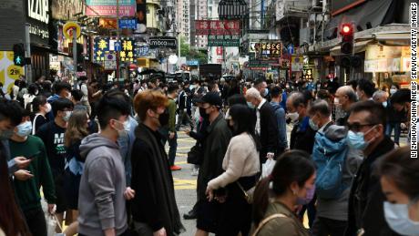 マスクを書いた人々が2021年12月22日、人口密度の高い香港のモンコック地域で道を渡っています。