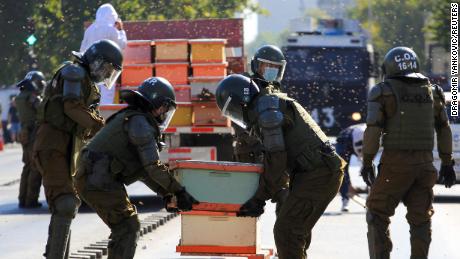 La police anti-émeute enlève des nids d'abeilles lors d'une manifestation à Santiago.