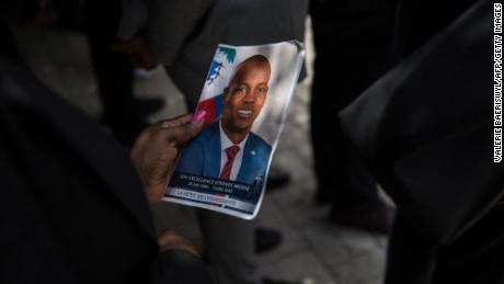 TOPSHOT - A guest holds a picture of late Haitian President Jovenel Moise during a ceremony at the National Pantheon Museum in Port-au-Prince, Haiti, on July 20, 2021. - The ceremony comes as designated Prime Minister Ariel Henry prepared to replace interim Prime Minister Claude Joseph,  after the July 7 attack at Moïse&#39;s private home. (Photo by Valerie Baeriswyl / AFP) (Photo by VALERIE BAERISWYL/AFP via Getty Images)