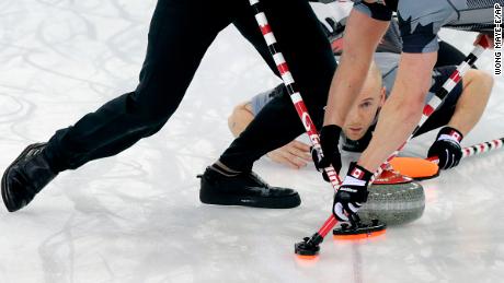Canada&#39;s Ryan Fry delivers the rock while teammates Ryan Harnden (left) and E.J. Harnden (right) sweep the ice during the men&#39;s curling gold medal game against Britain at the 2014 Winter Olympics.