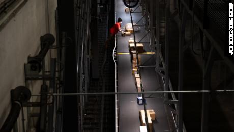 An employee removes packages from a moving conveyor belt in a loading area of the UPS Centennial Ground Hub on December 6, 2021 in Louisville, Kentucky.