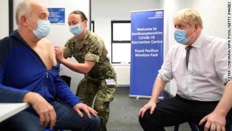 Britain&#39;s PM Boris Johnson looks on while Gordon Halfacre receives a vaccine from Cpl. Lorna MacDonald on January 6, 2022 in Northampton, England.