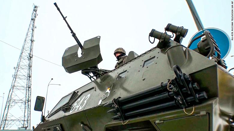 In this image taken from footage provided by Russian television, a Kazakh soldier stands atop of a military vehicle at a check point on Friday, January 7.