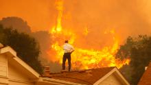 CAMARILLO, CA - MAY 3:  A man on a rooftop looks at approaching flames as the Springs fire continues to grow on May 3, 2013 near Camarillo, California. The wildfire has spread to more than 18,000 acres on day two and is 20 percent contained.  (Photo by David McNew/Getty Images)