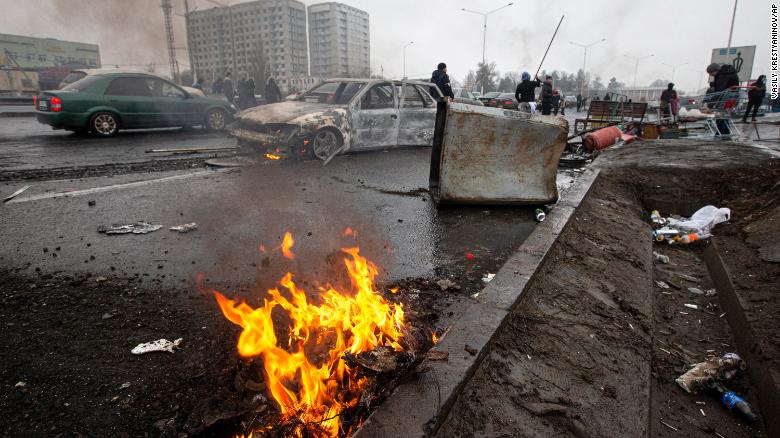 People walk past cars that were burned after clashes, on a street in Almaty, Kazakhstan on Friday, January 7.