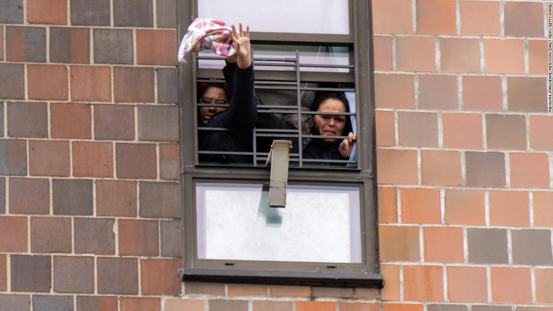 People wave from a window to catch the attention of emergency personnel. 