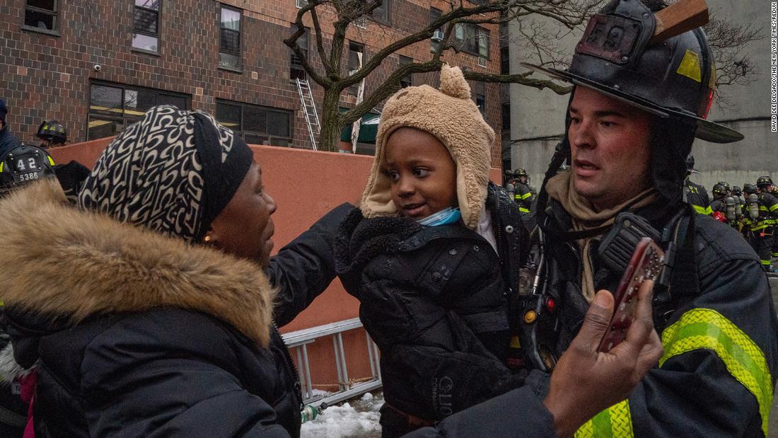 A child is returned to their mother by a firefighter at the scene of the fire. 