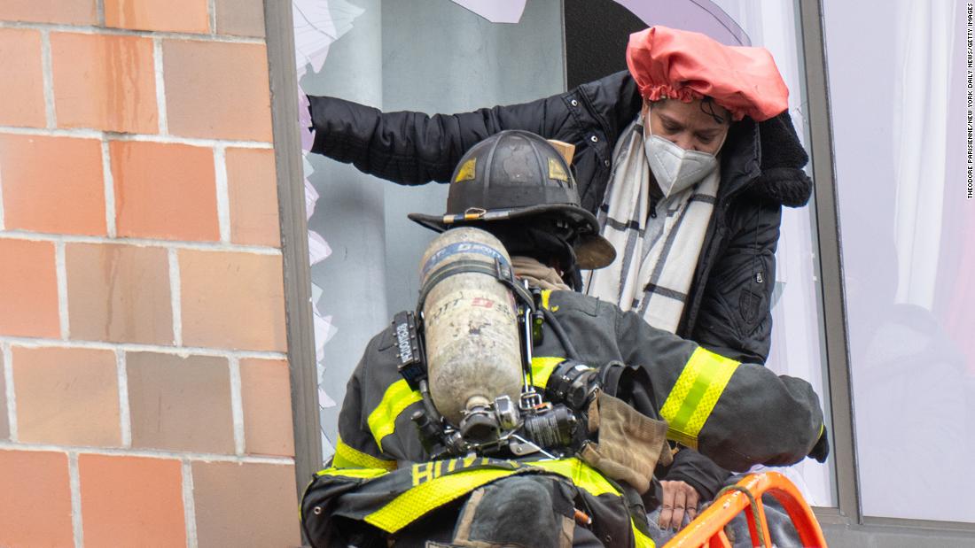 A firefighter helps a victim climb out a broken window to evacuate the building. 