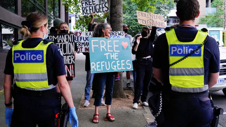 Police personnel watch pro-refugee protestors rally outside the Park Hotel, where Serbian tennis player Novak Djokovic is believed to be held, in Melbourne, Australia, January 10.