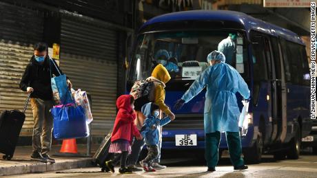 A worker in a protective suit helps bring residents to quarantine after new cases were reported on January 9 in Hong Kong.