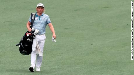 Smith carries his own golf bag as his caddie cleans the fairway bunker on the second hole during the third round of the Masters in 2021.