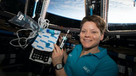 NASA astronaut Anne McClain is shown holding biomedical gear for MARROW on the International Space Station.