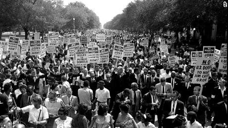The Reverend Martin Luther King Jr., center, arms raised, walks along Constitution Avenue with other civil rights protesters to the Lincoln Memorial during the March on Washington on August 28, 1963. 