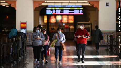 A family with masks walks through Union Station in Los Angeles